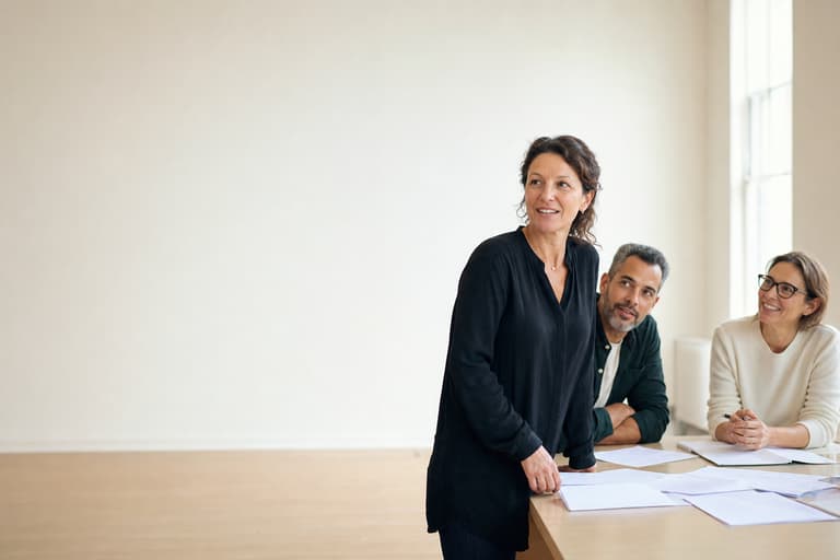 Three colleagues reviewing documents around a table