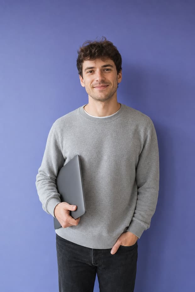 A young man carrying a closed laptop